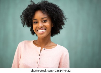 Close up portrait beautiful young black woman smiling against green background