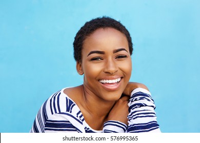 Close Up Portrait Of Beautiful Young Black Fashion Woman Smiling Against Blue Wall