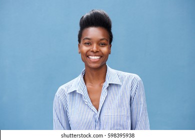 Close up portrait of beautiful young black woman smiling against blue background