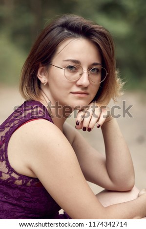 Close up portrait of a beautiful young caucasian woman, clean fresh face close up. Fashionable girl with trendy glasses and short hair posing outdoor. 