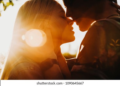 Close up portrait of a beautiful young couple waiting to kiss in their traveling time against sunset light.