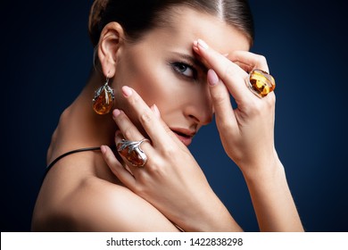 A close up portrait of a beautiful young dark-haired woman posing in the studio over the black background. Beauty, cosmetics, skincare, jewelry.