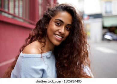 Close up portrait of beautiful young Indian woman smiling outside in city