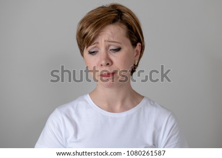 Close up portrait of a beautiful young red haired caucasian woman with a sad face. looking miserable and melancholy. Human facial expressions and emotions concept. Grey background