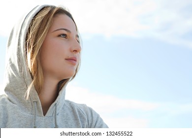 Close up portrait of a beautiful young sports woman wearing a hood during a sunny morning against a blue sky.