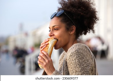 Close Up Portrait Of A Beautiful Young Woman Eating Sandwich Outdoors