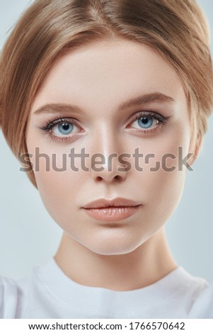 Close up portrait of a beautiful young woman with blonde hair and natural make-up. Studio shot on a white background. Beauty industry.