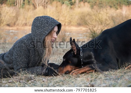 Close up portrait of beautiful young woman with her doberman dog. Warm natural color.
