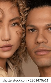 Close up portrait of a biracial man in his 30's and a multiracial woman in her 20's looking at the camera on a neutral background. Stock Photo