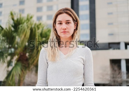 Close up portrait of blonde caucasian young woman looking serious at camera. Pretty teenage girl staring front with sad attitude. High quality 4k footage