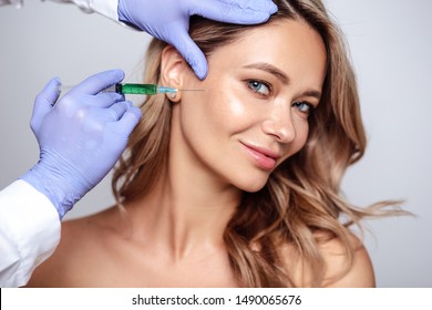 Close up portrait of blonde woman with cosmetologist hands near her face. Procedure in salon, spa and care