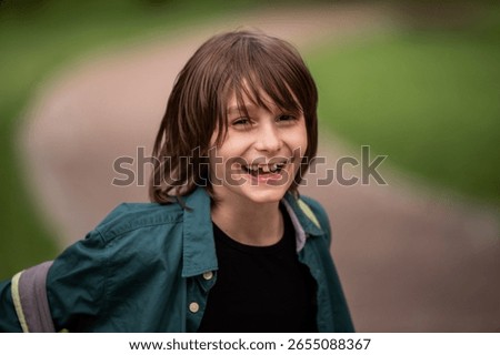Close up portrait of boy with missing front teeth laughing in park.