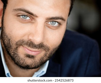 Close up portrait of a businessman wearing a suit and smiling slightly, showing his beautiful green eyes - Powered by Shutterstock