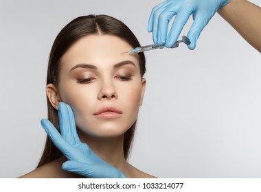 Close up portrait of calm female face. Young woman is getting collagen injection into her forehead. Isolated and copy space