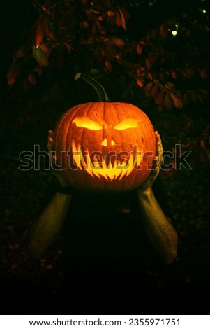 Close up portrait of carved pumpkin head Jack-o-lantern man hold in his hand in scary night