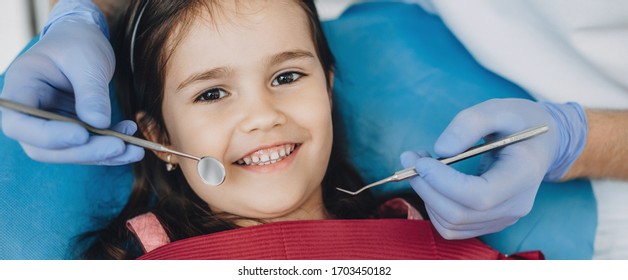 Close up portrait of a caucasian girl having an examination at the pediatric dentist while smiling at camera