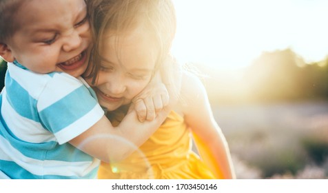 Close up portrait of a caucasian small boy embracing his sister while playing together outside