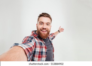 Close up portrait of a cheerful bearded man taking selfie over white background - Shutterstock ID 513884902