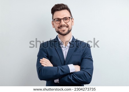 Close up portrait of a cheerful man in glasses and dark blue suit. Isolated on grey background