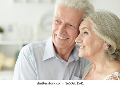 Nahaufnahme eines Porträts von fröhlichem Seniorenpaar, das zu Hause umarmt