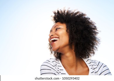 Close Up Portrait Of Cheerful Young Black Woman Laughing Outdoors Against Bright Sky