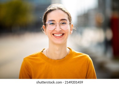 Close Up Portrait Of Cheerful Young Caucasian Woman With Eyeglasses Standing Outside In The City