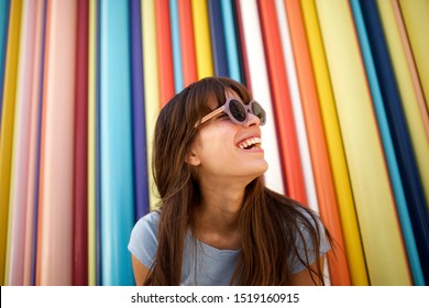 Close Up Portrait Of Cheerful Young Woman Laughing With Sunglasses Against Colourful Background 