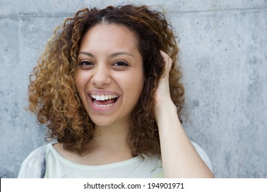 Close Up Portrait Of A Cheerful Young Woman Laughing With Hand In Hair