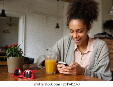 Close up portrait of a cheerful young woman typing a text message on mobile phone - Powered by Shutterstock