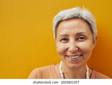 Close Up Portrait Of Confident Mature Woman Posing Against Yellow Background And Looking At Camera, Copy Space