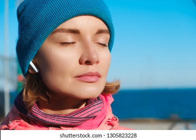 Close Up Portrait Of A Confident Woman At The Seaside Listening To Music In Ear Pods