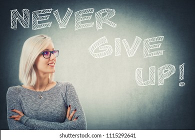 Close up portrait confident young woman and crossed arms  wearing glasses over grey wall background and the text never give up  Motivational words  positive thinking concept 
