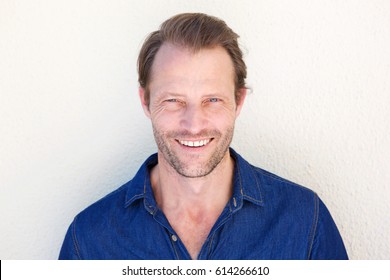 Close Up Portrait Of Cool Older Man Smiling Against White Wall