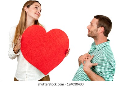 Close up portrait of couple playing around with big red heart symbol.Isolated on white background.