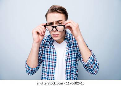 Close Up Portrait Of Curious Teen Man In Street Style Wear Narrowed His Eyes And Look Over Glasses At Camera Isolated On Light Blue Background