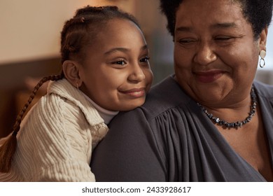 Close up portrait of cute African American little girl embracing smiling grandmother at home - Powered by Shutterstock