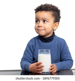 Close Up Portrait Of Cute Afro American Boy Holding Glass Of Milk At Table. Kid With Milk Mustache Isolated Against White Background.