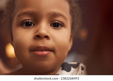 Close up portrait of cute Black little girl with big eyes looking at camera at home, bokeh effect, copy space - Powered by Shutterstock