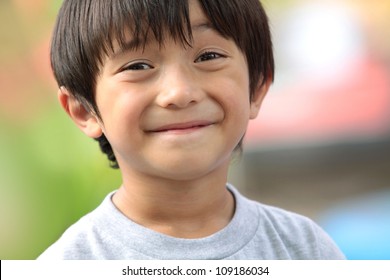 Close Up Portrait Of Cute Boy Smiling In The Park