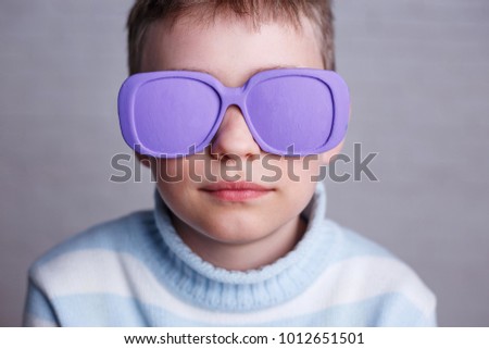 Close up portrait of cute boy in violet sunglasses with opaque lenses