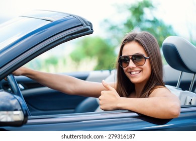 Close Up Portrait Of Cute Girl Driving Convertible Doing Thumbs Up.