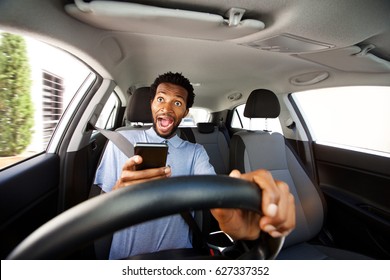 Close Up Portrait Of Distracted Man Driving In Car Holding Phone