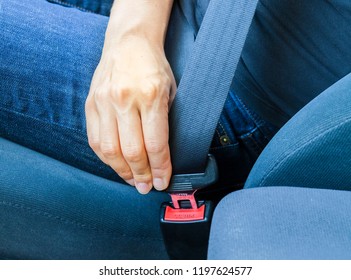 Close up portrait of a driver hand fastening seat belt in a car