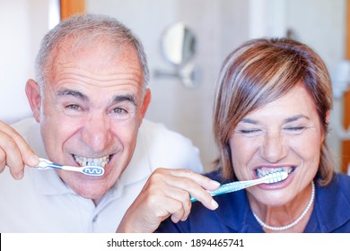 Close portrait of an elderly couple brushing their teeth nicely in the bathroom at home - Powered by Shutterstock