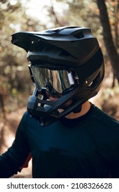 Close up of Portrait of enduro mtb or downhill mtb rider on mountain trail. Black full face helmet, goggles, blue gloves and cycling gear in the forest in winter. - Shutterstock ID 2108326628