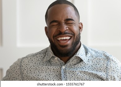 Close up portrait of excited african American man in good mood laughing at funny joke, overjoyed biracial male laughter have fun smiling giggling showing white healthy teeth, dental treatment - Powered by Shutterstock