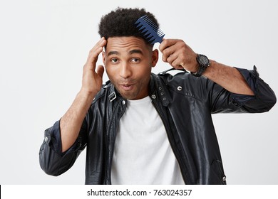 Close Up Portrait F Young Attractive Black-skinned African Male Student With Curly Hair In Stylish Outfit Combing Hair In Front Of Mirror With Funny Ace Expression, Getting Ready For Party.