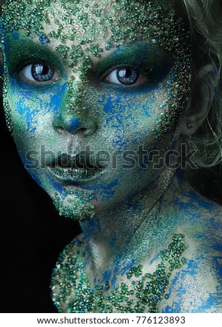 close up portrait of fantastic colorful young girl. professional creative  makeup with beads on face. paint on face. blue and green body art