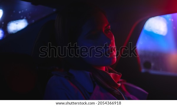 Close Up\
Portrait of a Female Commuting Home in a Backseat of a Taxi at\
Night. Beautiful Woman Passenger Looking Out of Window while in a\
Car in City Street with Working Neon\
Signs.