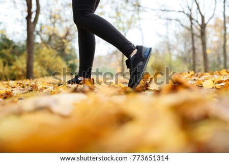 Close up portrait of a female feets in sneakers walking at the park